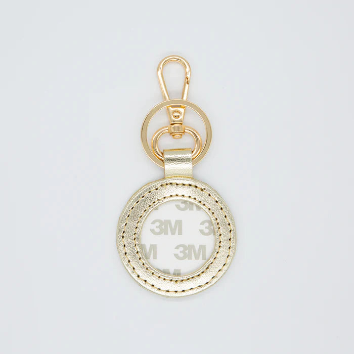 Gold keychain with '3M' branding on a light gray background