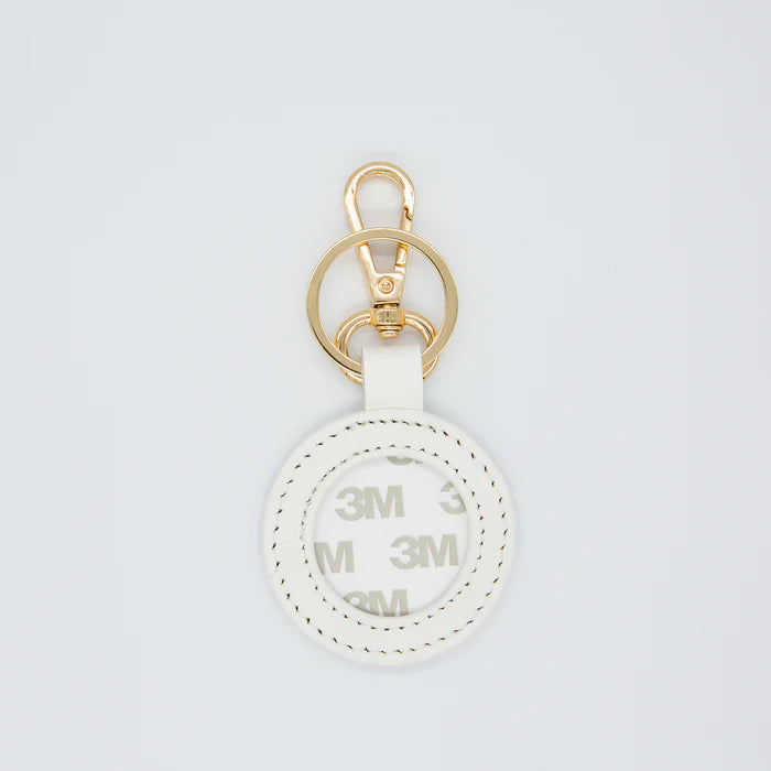 White keychain with gold ring on a light gray background